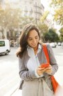 Smiling woman using cell phone in the city — Stock Photo