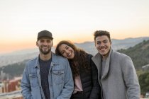 Портрет трех счастливых друзей на холме на закате — стоковое фото
