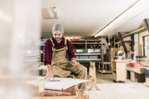 Arbeiter mit Tablet schaut sich Entwurf in Werkstatt an — Stockfoto