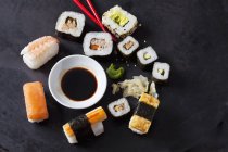 Varietà di sushi con wasabi, zenzero e ciotola di salsa di soia su terreno scuro — Foto stock