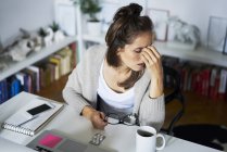 Young woman at home at desk suffering headache — Stock Photo