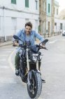 Ritratto di giovane urlante seduto sulla moto e tirando facce divertenti — Foto stock