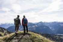 Austria, Tirol, pareja joven de pie en el paisaje de montaña y mirando a la vista - foto de stock