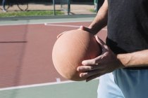 Мужчина держит баскетбол на баскетбольной площадке — стоковое фото