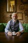 Портрет элегантного пожилого человека, сидящего на диване в кафе — стоковое фото