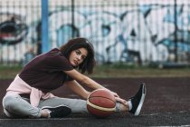 Молодая женщина с баскетбольными растяжками на открытой площадке — стоковое фото