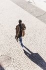 Empresario caminando al aire libre con maletín, teléfono celular y auriculares - foto de stock
