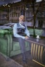 Homem sênior elegante sentado no sofá em um café e olhando pela janela — Fotografia de Stock