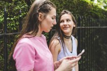 Two teenage girls with cell phone outdoors — Stock Photo