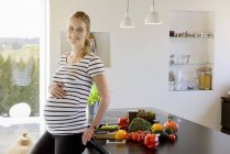 Retrato de mulher grávida sorridente na cozinha em casa — Fotografia de Stock