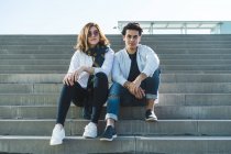 Портрет стильной молодой пары, сидящей на лестнице на улице — стоковое фото