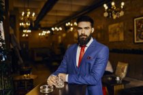 Portrait of elegant young man in a bar with tumbler — Stock Photo