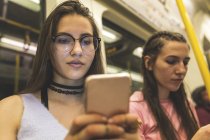 Adolescente utilisant un téléphone portable dans le métro — Photo de stock