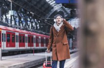 Young man with guitar case and headphones at station platform — Stock Photo