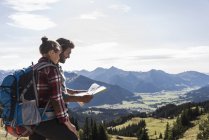 Autriche, Tyrol, jeune couple regardant la carte en paysage montagneux — Photo de stock