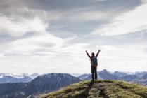 Austria, Tirolo, giovane donna in piedi nel paesaggio montano e tifo — Foto stock