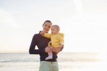 Мама тримає маленьку доньку на пляжі — стокове фото