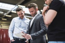 Drei Männer teilen sich Tablet in Fabrikhalle — Stockfoto