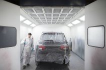 Pittore auto pittura una macchina all'interno di una cabina di vernice — Foto stock