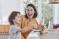 Glückliche Mutter und Sohn spielen zu Hause mit Modellboot — Stockfoto
