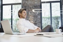 Reifer Geschäftsmann mit Laptop im modernen Büro — Stockfoto