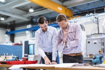 Two men in factory looking at plan — Stock Photo