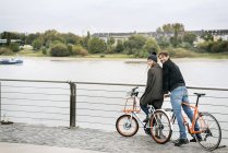 Smiling couple with bicycles at the riverside — Stock Photo