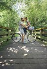 Couple with bicycle about to kiss on a wooden walkway in the countryside — Stock Photo