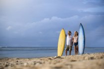 Affettuosa coppia anziana con tavole da surf in spiaggia — Foto stock