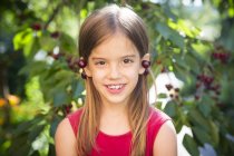 Маленька дівчинка з вишнями на вухах. — стокове фото