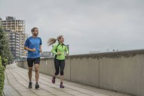 Reino Unido, Inglaterra, Londres, Greenwich, pareja adulta corriendo en la ciudad - foto de stock
