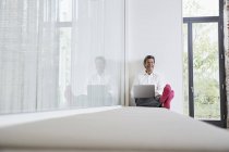 Riendo hombre de negocios con calcetines de color rosa utilizando el ordenador portátil en la oficina - foto de stock