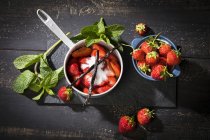 Fresas frescas azucaradas en maceta, vainilla bourbon y menta - foto de stock