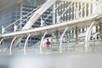 Runner in camicia fitness rossa che corre sul ponte moderno — Foto stock