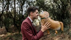 Homme en costume en forêt jouant avec ballon drôle en forme de chien — Photo de stock