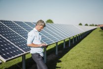 Geschäftsmann nutzt Tablet im Solarpark — Stockfoto