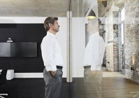 Reifer Geschäftsmann reflektiert in der Glasscheibe eines modernen Konferenzraums — Stockfoto