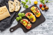 Bruschetta, ciabatta con pomodori multicolori e basilico — Foto stock