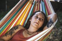 Porträt einer jungen Frau mit Tätowierung in der Hängematte liegend — Stockfoto