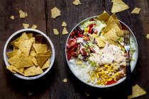 Taco-Salatschüssel mit Reis, Mais, Chili con Carne, Nierenbohnen, Eisbergsalat, Sauerrahm, Nacho-Chips, Tomaten — Stockfoto