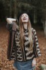 Портрет сміху молодої жінки носить капелюх і пончо в осінньому лісі — стокове фото