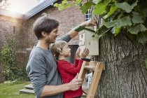 Vater und Tochter hängen Nistkasten im Garten auf — Stockfoto