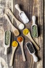 Spicies, curry, chilli, cinnamon, curcuma, garlic, parsley, oregano, salt and pepper on wooden spoons — Stock Photo