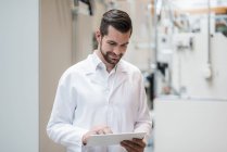 Man wearing lab coat in factory using tablet — Stock Photo