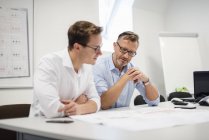 Due uomini d'affari discutono il piano sulla scrivania in ufficio — Foto stock