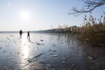 Deutschland, brandenburg, straussee, zugefrorener see und silhouetten von zwei menschen, die auf eis gehen — Stockfoto