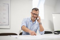 Reifer Geschäftsmann telefoniert am Schreibtisch im Büro — Stockfoto