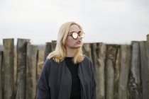 Retrato de jovem loira vestindo óculos de sol espelhados na praia — Fotografia de Stock