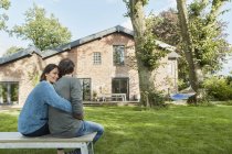 Smiling affectionate couple sitting in garden of their home — Stock Photo