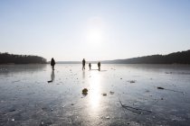 Deutschland, brandenburg, straussee, zugefrorener see und silhouetten von menschen, die auf eis gehen — Stockfoto